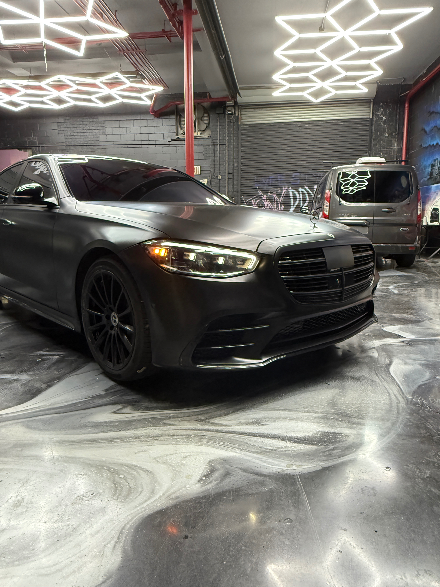 Satin black Mercedes S-Class under the hex lights in our shop