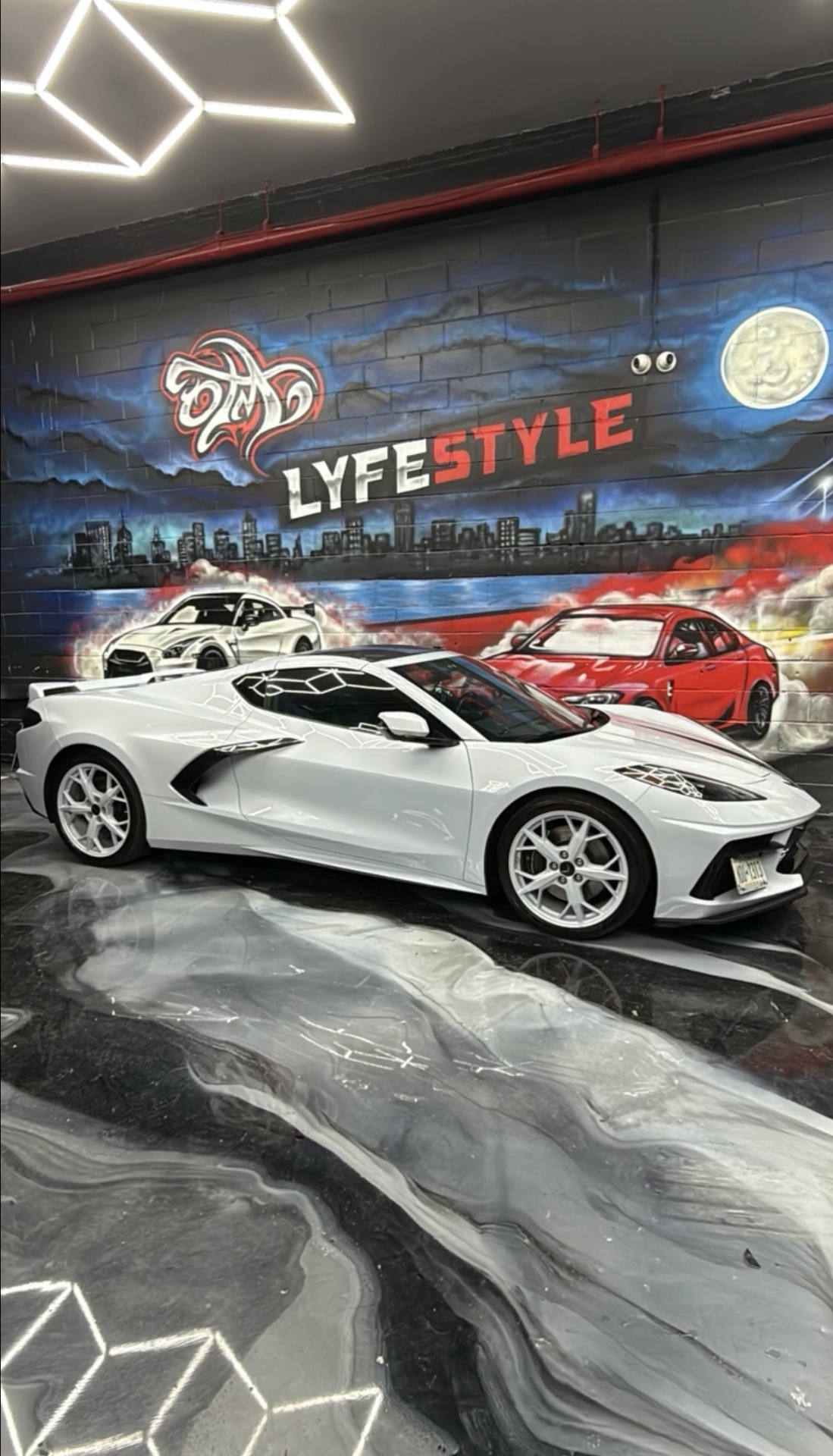 White Corvette C8 in front of the Lyfestyle mural